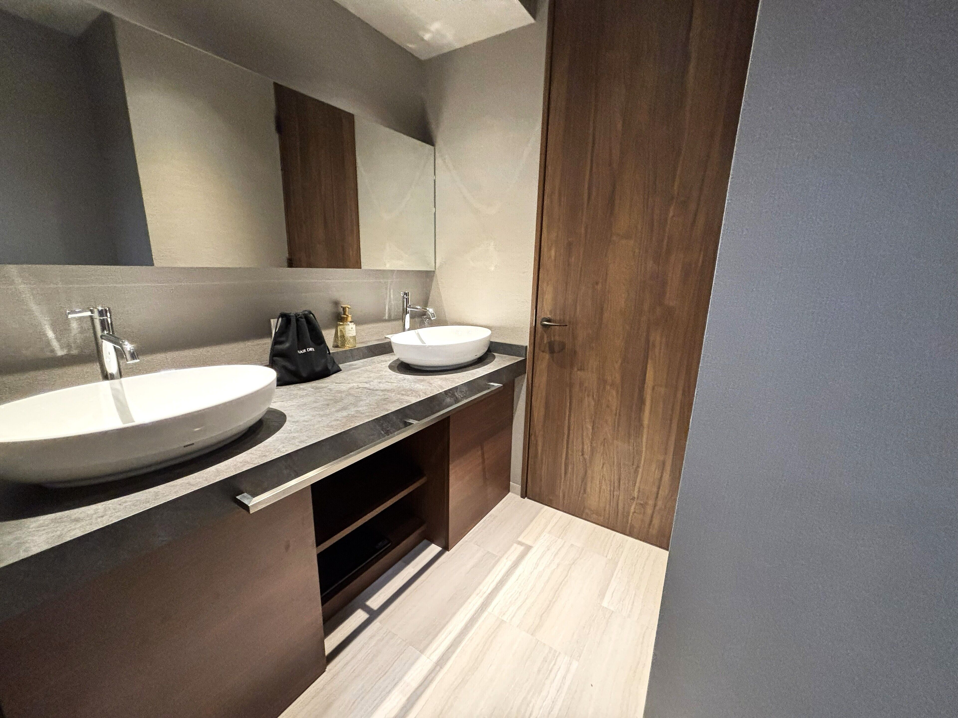 Un bagno moderno con due lavabi, uno specchio grande e mobili in legno.