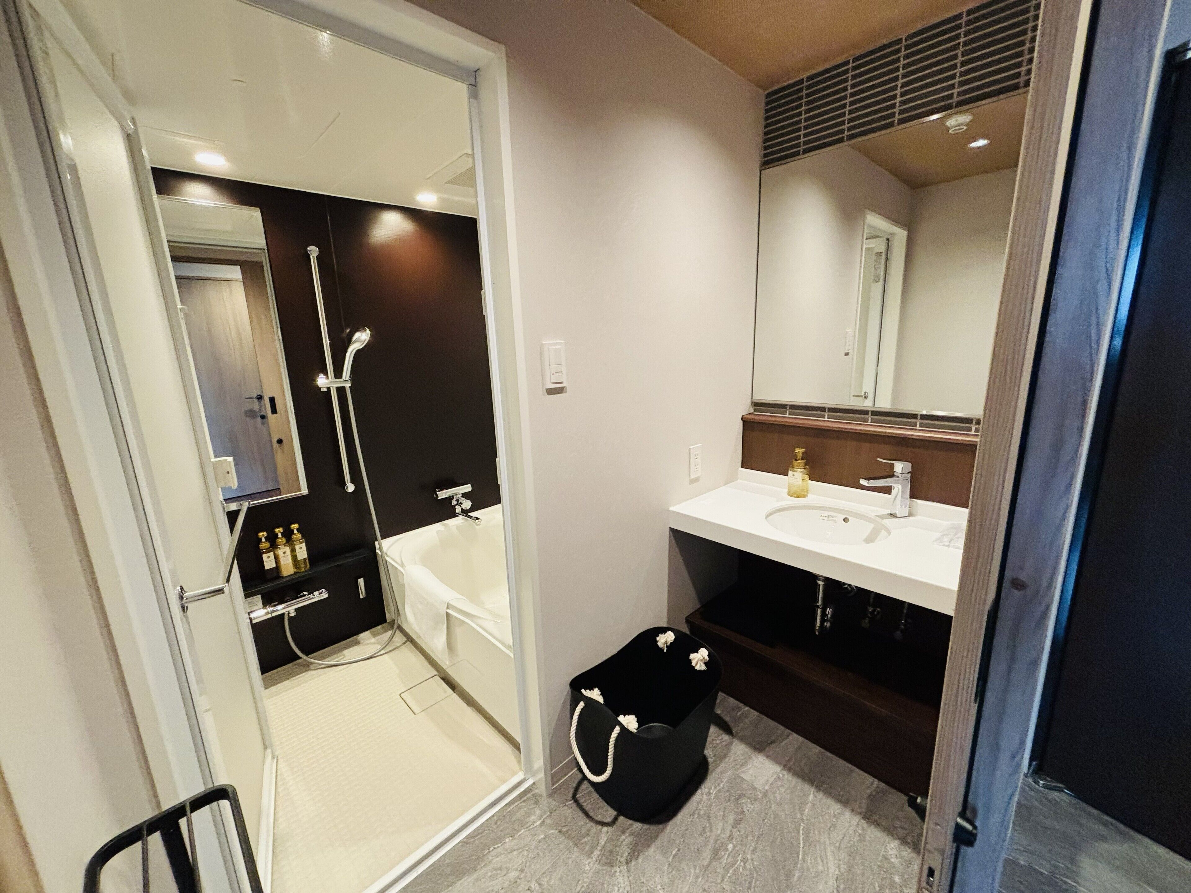 A modern bathroom with a glass-enclosed shower, a white sink, and a dark vanity.