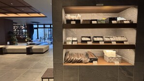 A modern interior with a seating area, a display of packaged goods, and a view of the outside. - Usa GRAND HOTEL (Usa)