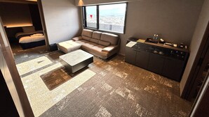 A compact living space with a sofa, a small table, a kitchenette, and a bed. - Usa GRAND HOTEL (Usa)