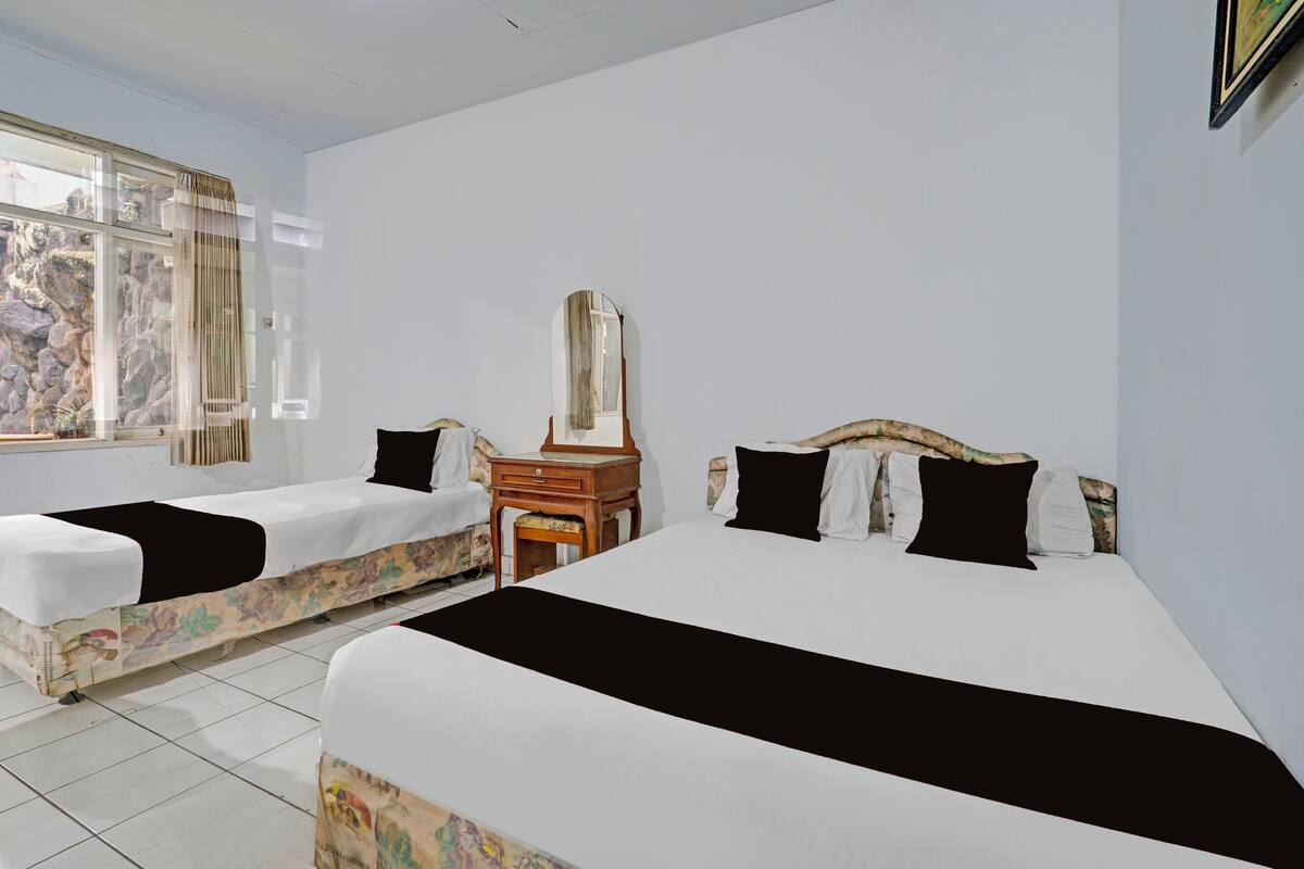 A hotel room with two beds, a dresser, a mirror, and a window with curtains.