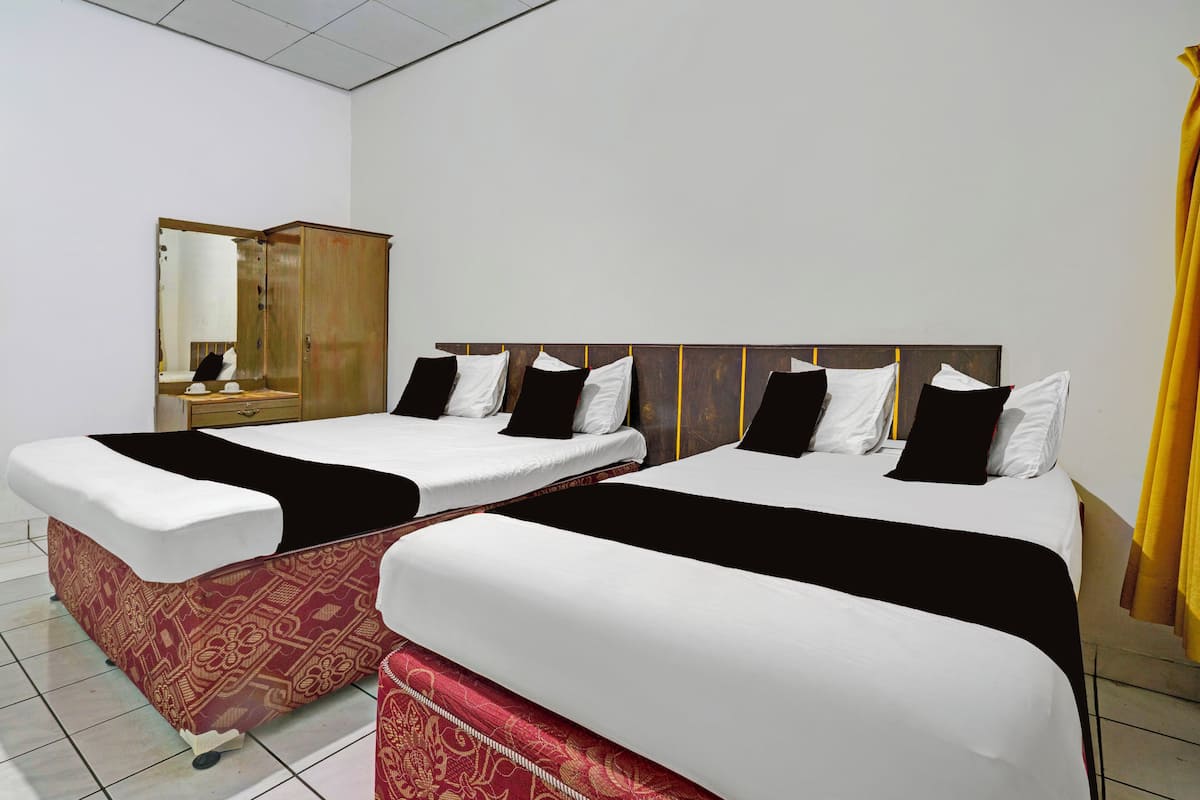 A hotel room with two beds, a wooden headboard, a mirror, and a wardrobe.