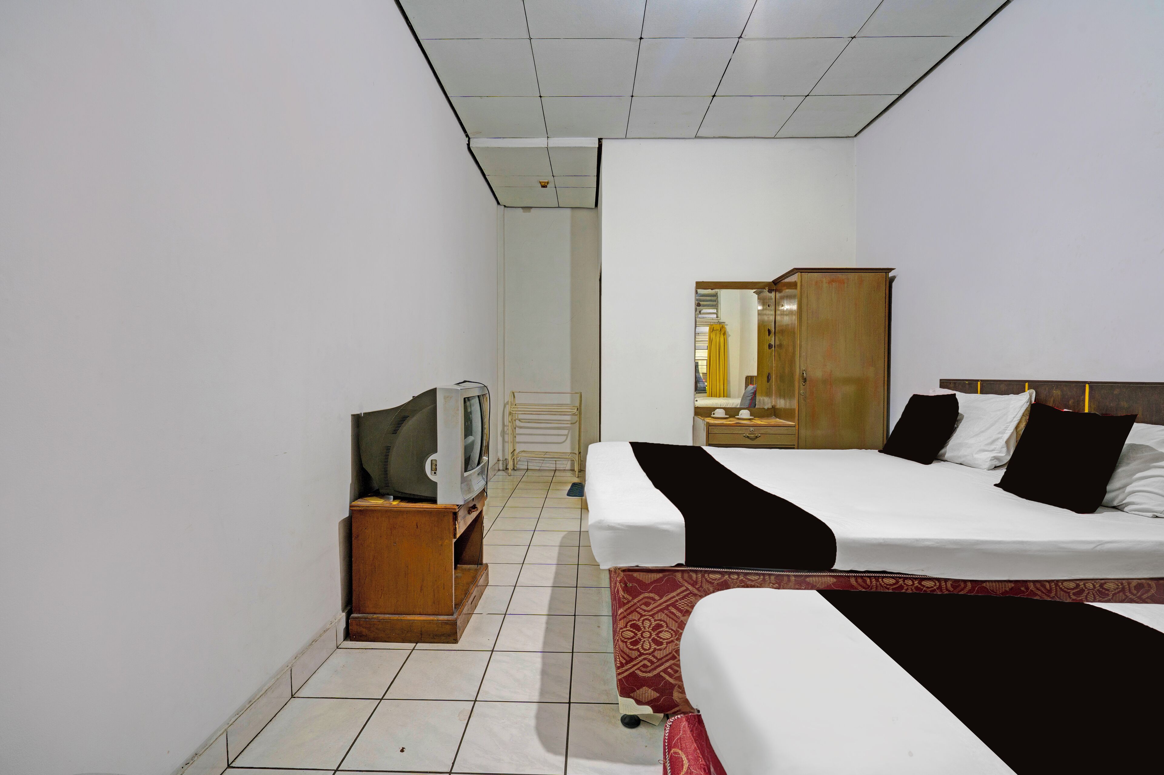 A hotel room with a bed, a TV, a wardrobe, and a bathroom visible through an open door.