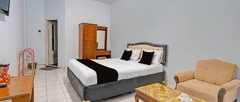 A bedroom with a bed, a wooden dresser, a chair, and a small table.