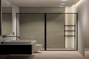 A modern bathroom with a large mirror, a white sink, a toilet, and a glass shower enclosure.