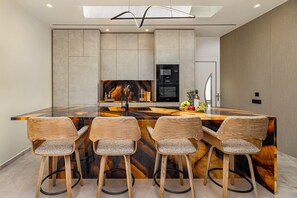 A modern kitchen with a central island, bar stools, and built-in appliances.
