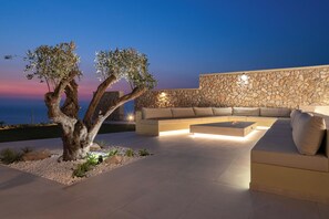 A modern outdoor seating area with a stone wall and a tree.