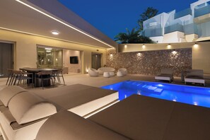 A modern outdoor pool area with lounge chairs and a dining setup.