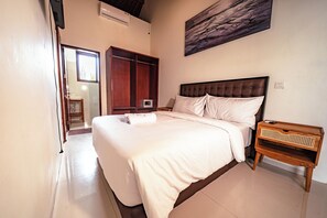A bedroom with a large bed, a wooden wardrobe, a bedside table, and a wall-mounted air conditioner. - Hidden Oasis in Seminyak – Spacious 5BR Luxury Villa with Pool & Cinema Room (Seminyak, Kuta, Badung Regency)