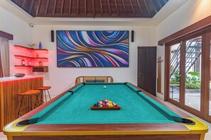 A pool table with a colorful ball setup, a bar area with stools, and a large abstract painting on the wall. - Hidden Oasis in Seminyak – Spacious 5BR Luxury Villa with Pool & Cinema Room (Seminyak, Kuta, Badung Regency)