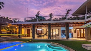 Ein modernes Haus mit Swimmingpool, Sitzgelegenheiten im Freien und einer Hängematte.