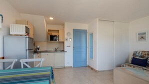A compact living space with a kitchenette, a dining area with a table and chairs, and a sofa with a patterned cover.