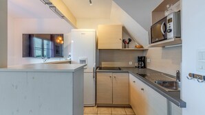A modern kitchen with a refrigerator, microwave, stove, and sink. - Seaside house for 4 people with a swimming pool (Saint-Nic)