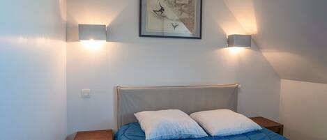 Un dormitorio con una cama, dos lámparas de noche y un cuadro en la pared.