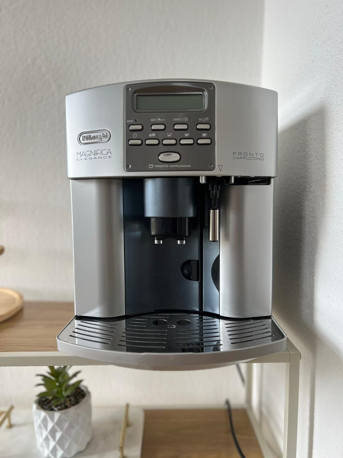 Een strakke, moderne espressomachine met een digitaal scherm en meerdere bedieningsknoppen, op een wit aanrecht.