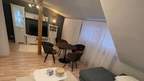 Un salon moderne comprenant un ensemble de canapés, une table basse et un coin repas avec des chaises et une table.