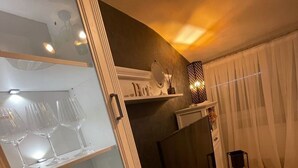 Un salon comprenant un téléviseur, un meuble avec des portes en verre et une étagère ornée d’objets décoratifs.
