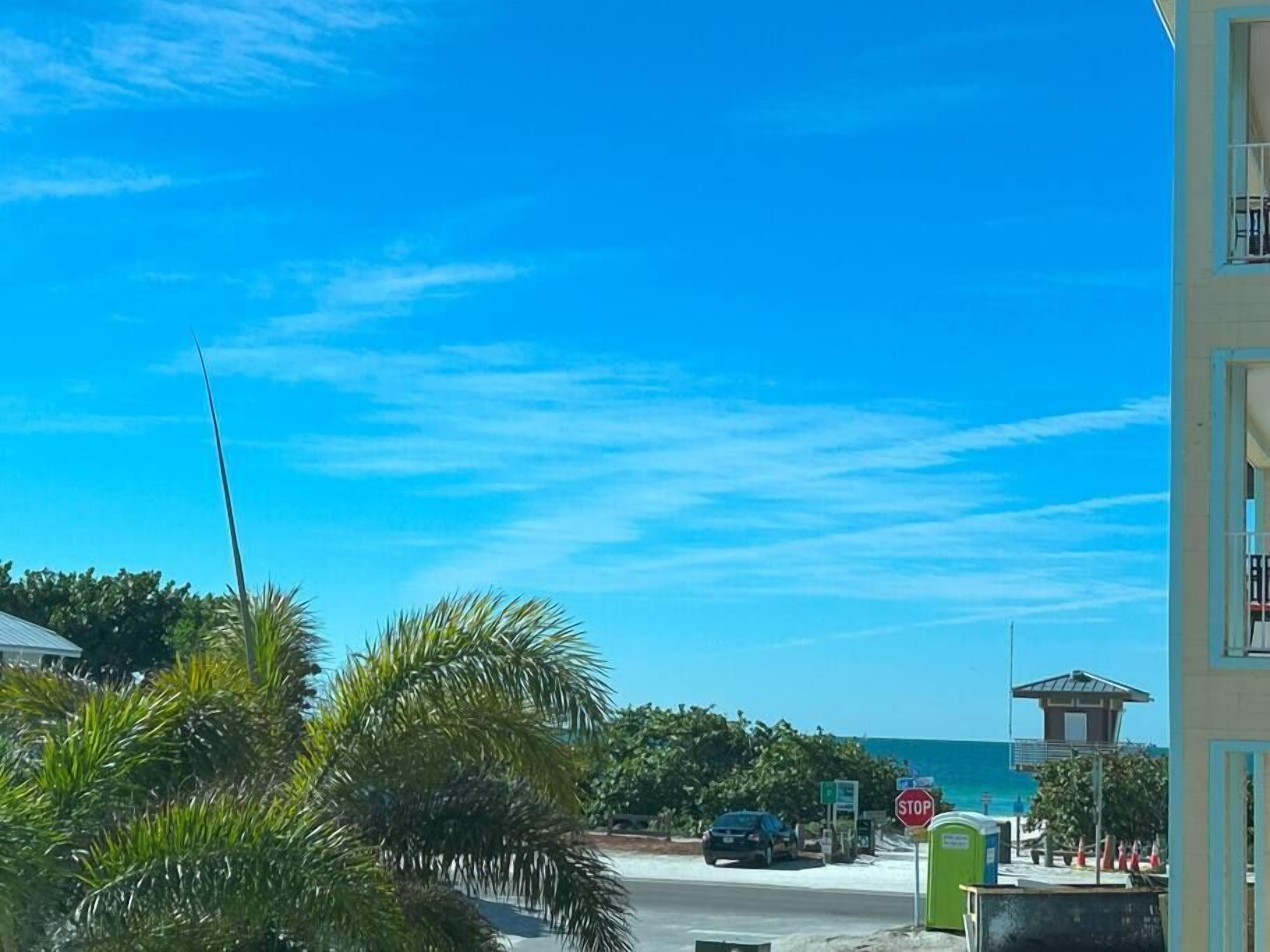 A coastal road with a stop sign, a guard tower, and a beach visible in the distance.