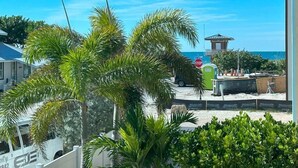A view of a beachside area with palm trees, a stop sign, and a small building in the background. - AMI Cortez Beach Retreat "Views" Resort-style Pool + WiFi + Dog-friendly (Bradenton Beach)