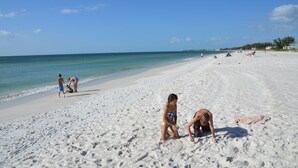 A sandy beach with people playing and relaxing. - AMI Cortez Beach Retreat "Views" Resort-style Pool + WiFi + Dog-friendly (Bradenton Beach)
