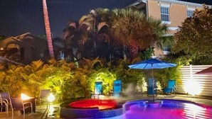 A nighttime pool area with a water feature, palm trees, and outdoor seating. - AMI Cortez Beach Retreat "Views" Resort-style Pool + WiFi + Dog-friendly (Bradenton Beach)