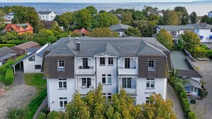 A multi-story residential building with balconies, a paved driveway, and a view of the sea. - Relaxing beach vacation at Villa Daheim in Breege-Juliusruh (Juliusruh)