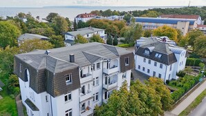 A multi-story residential building with a grey roof, white walls, and multiple balconies. - Relaxing beach vacation at Villa Daheim in Breege-Juliusruh (Juliusruh)