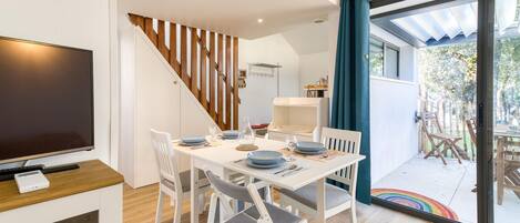 A modern dining area with a wooden staircase, a TV, and a view of the outdoors.