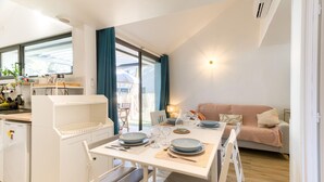 A compact kitchen with a dining area, a sofa, and a table set for two. - Maison accès plage direct (Meschers-sur-Gironde)
