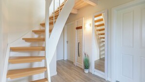 A staircase with wooden steps leading to a landing, a white door, and a potted plant.