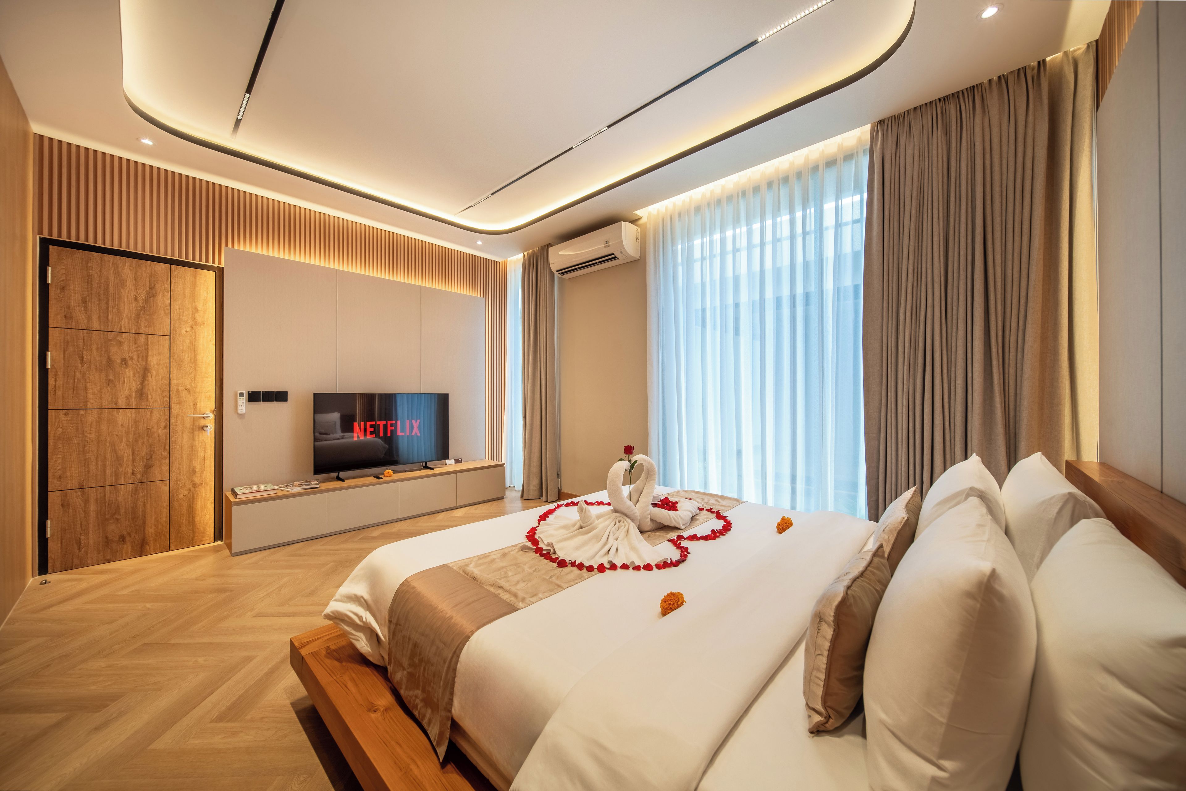 Una moderna camera d'albergo con un letto grande, una TV a schermo piatto e un condizionatore d'aria a parete.