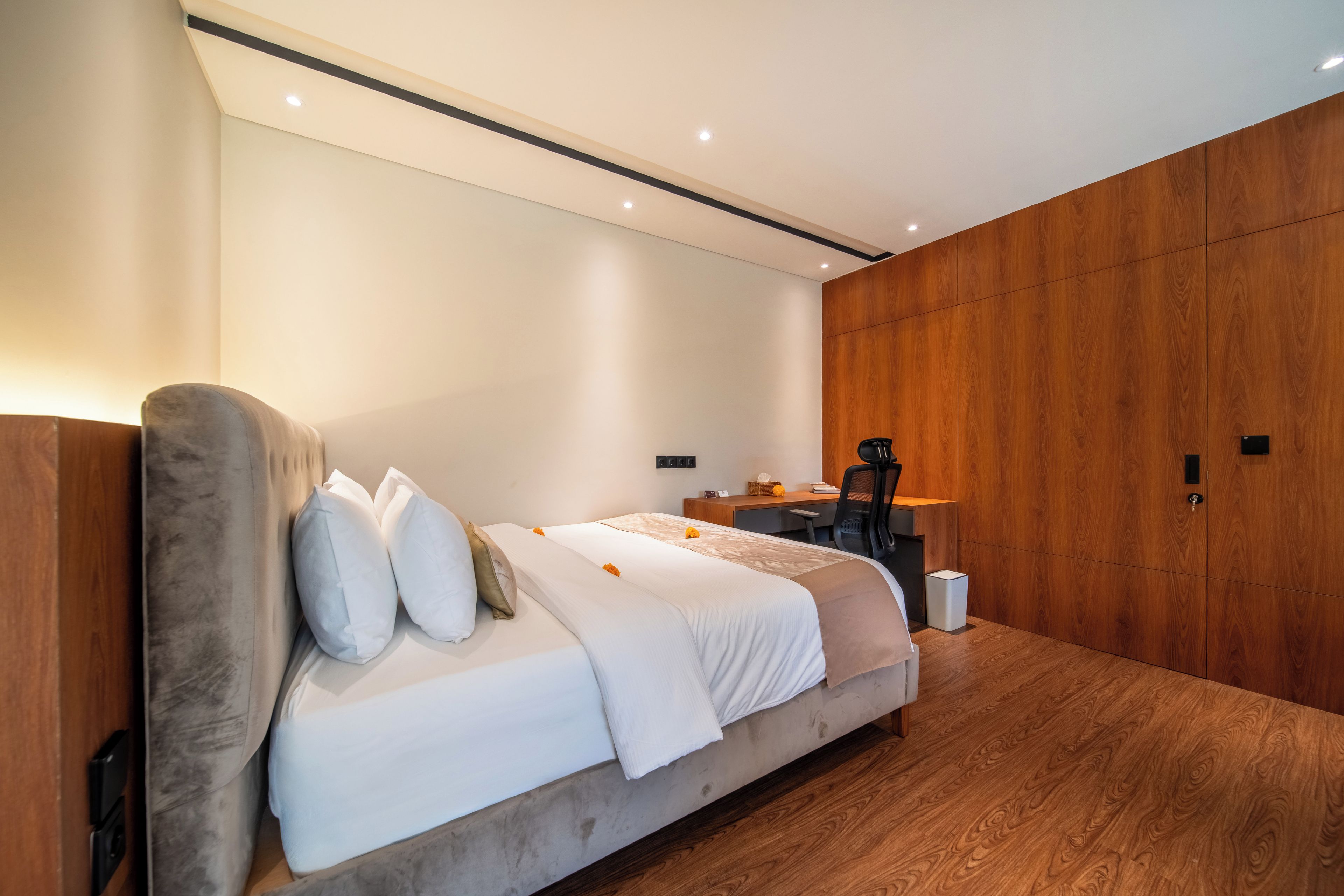 Een moderne slaapkamer met een groot bed, een houten garderobe en een bureau.