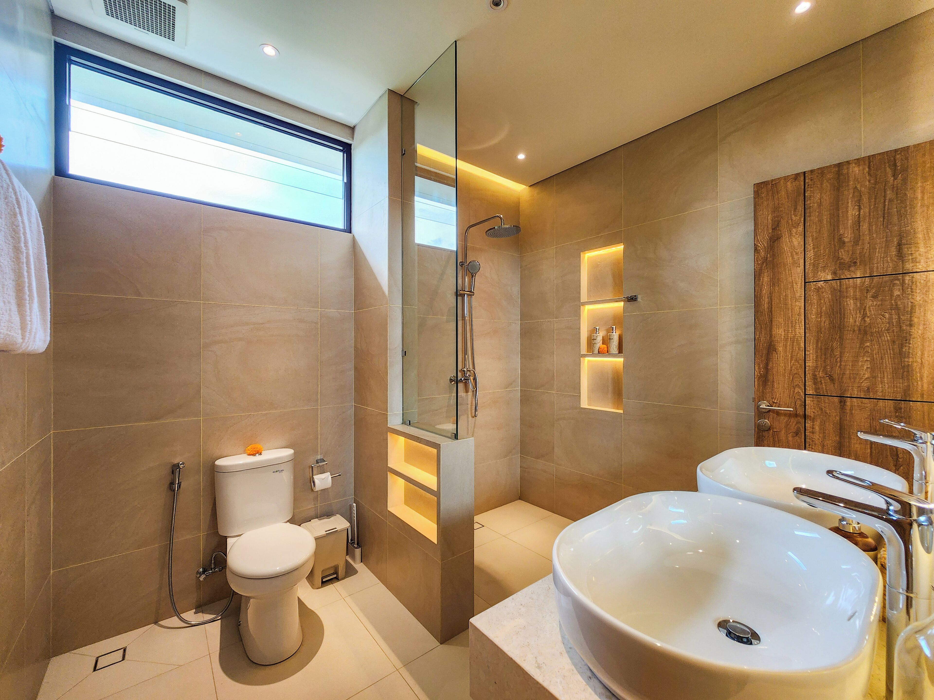 A modern bathroom with a toilet, bidet, and two sinks.