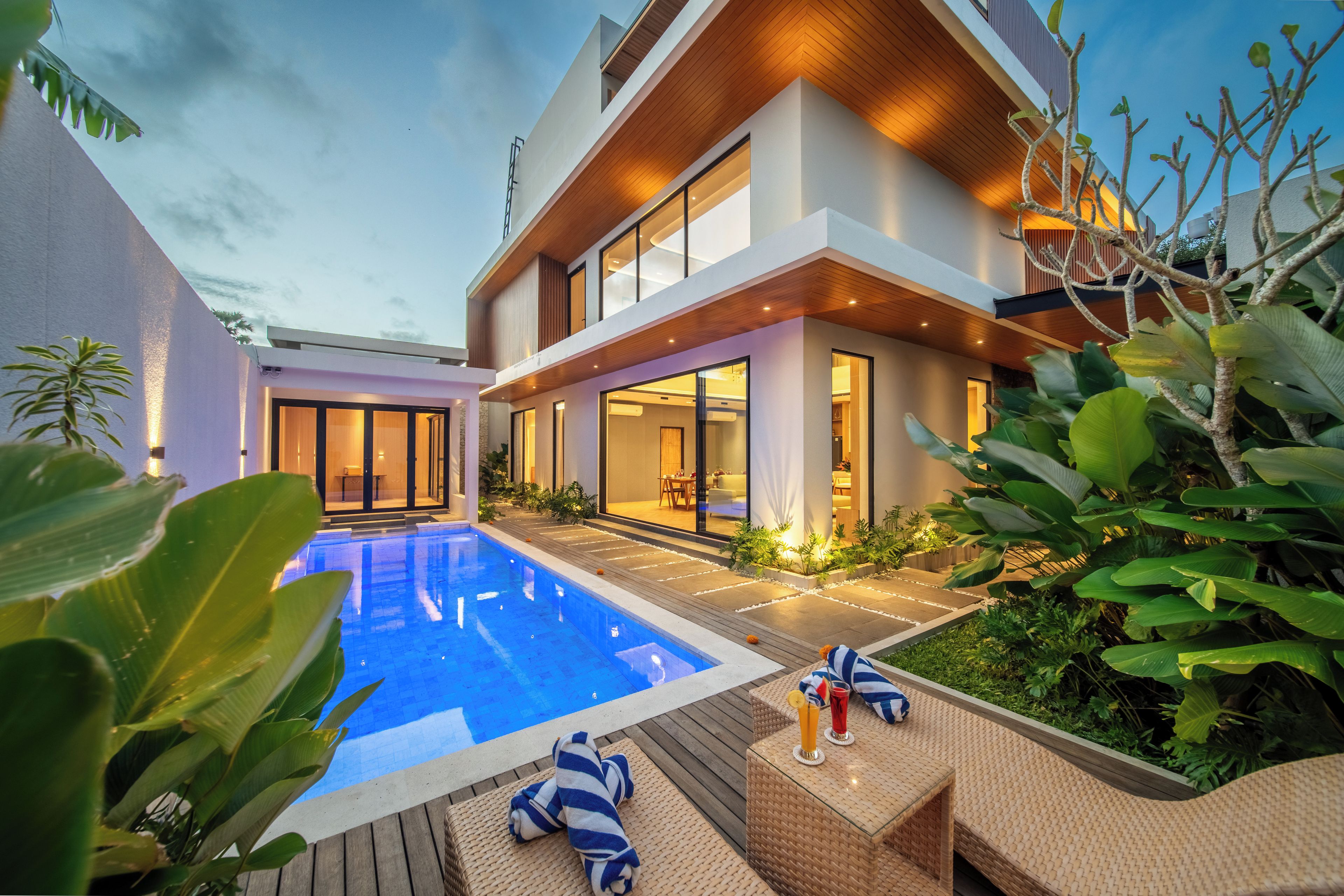 A modern house with a swimming pool, outdoor seating, and lush greenery.