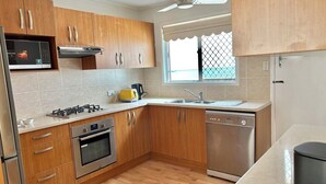 Une cuisine moderne avec des meubles en bois, des appareils en acier inoxydable et une fenêtre offrant une belle vue.