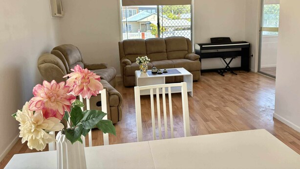 Un salon comprenant un canapé, une table basse, un piano et une fenêtre donnant sur une maison.
