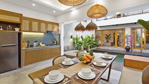 A modern kitchen with wooden cabinets, a stainless steel refrigerator, and a dining area with a table set for four.