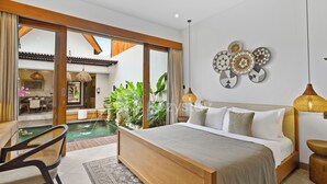 A bedroom with a large bed, a small table, and a view of a pool and dining area.