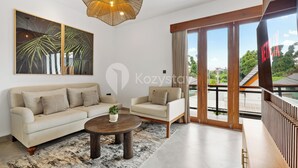 A modern living room with a sofa, armchair, coffee table, and artwork.