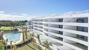 Un hôtel moderne doté de nombreux balcons, d’une piscine et d’un aménagement paysager luxuriant.