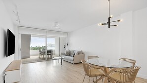 Un salon moderne avec une table à manger en verre, un canapé et un téléviseur.