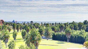 Un parcours de golf offrant une vue sur l’océan et sur un navire au loin.