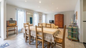 A dining area with a table set for four, wooden chairs, a wooden cabinet, and a television on a stand.