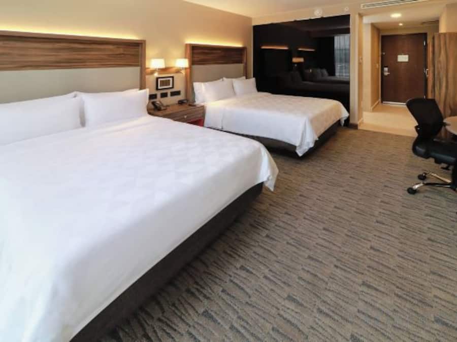 A hotel room with two beds, a desk, and a chair.