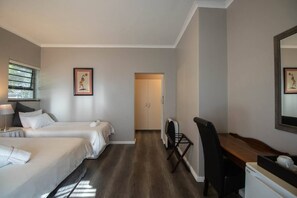 Camera d'albergo con due letti, una scrivania e una sedia.