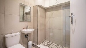 A modern bathroom with a toilet, sink, and glass-enclosed shower. - Spring Tide Inn - Standard king room 3 (Cape Town)
