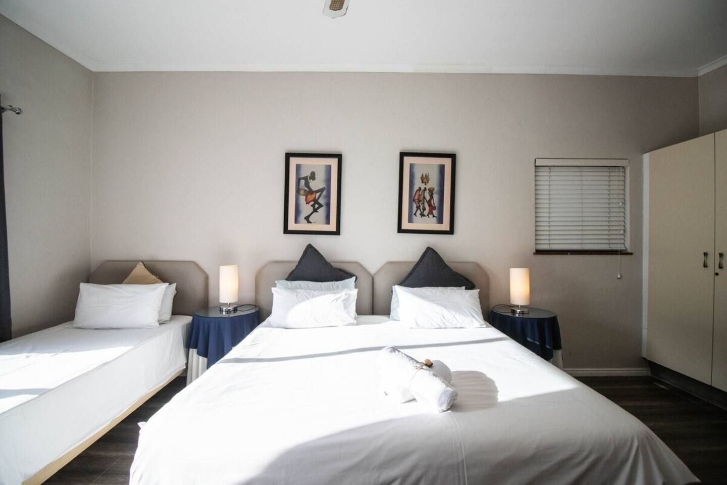 Habitació d'hotel amb un llit gran, dues taules de nit, dues làmpades i un armari.