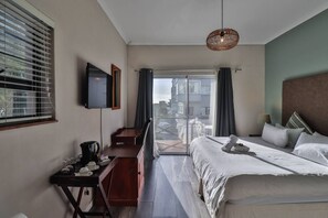 Une chambre d’hôtel équipée d’un lit, d’un bureau, d’une chaise, d’une télévision et d’un balcon avec vue.