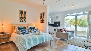 Un dormitorio con cama, sofá, lavadora y balcón con vistas.