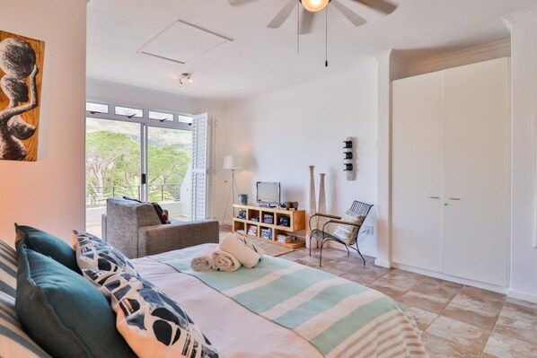 A spacious room with a bed, a sofa, a chair, a TV, and a wardrobe.